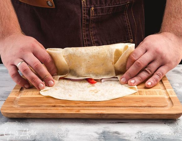 Заверните лаваш рулетом, чтобы он был полностью закрыт с обеих сторон.