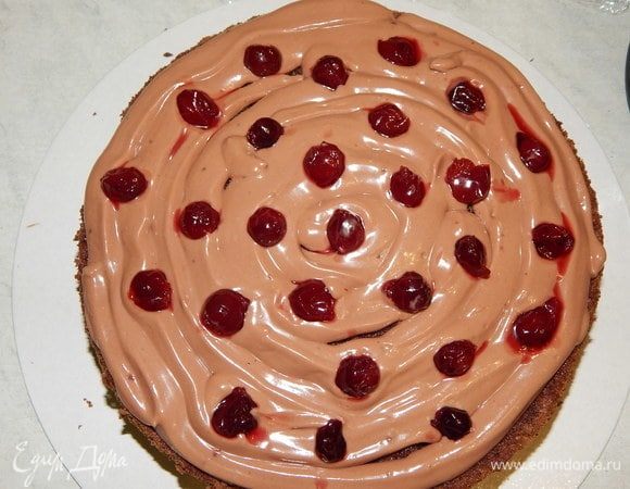 Из кондитерского мешка отсаживаем крем на корж, выкладываем вишню и сверху накрываем вторым коржом. Последний корж пропитать сиропом, но кремом не смазывать. Убрать торт в холодильник.