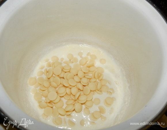 Приготовим шоколадный ганаш. В сотейнике разогреть сливки, выложить в горячие сливки белый шоколад и перемешать до растворения шоколада, добавить несколько капель розового красителя. Ганаш немного остудить.