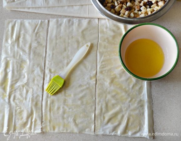 Тесто фило разморозьте при комнатной температуре. Аккуратно отделите листы друг от друга, смажьте лист растопленным сливочным маслом, сверху уложите еще один пласт и также смажьте маслом. Разрежьте сложенные листы теста на 3 части. Также проделайте и с другими листами фило.