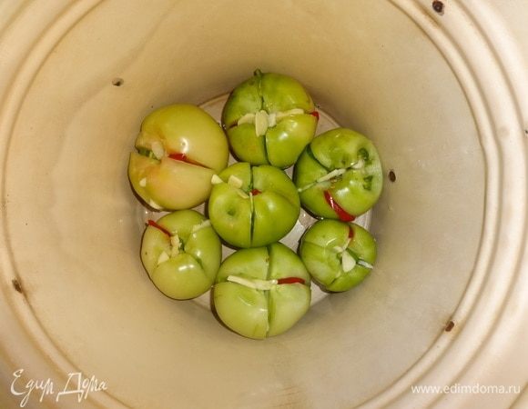 На дно эмалированного ведра или кастрюли уложить слой фаршированных помидоров.