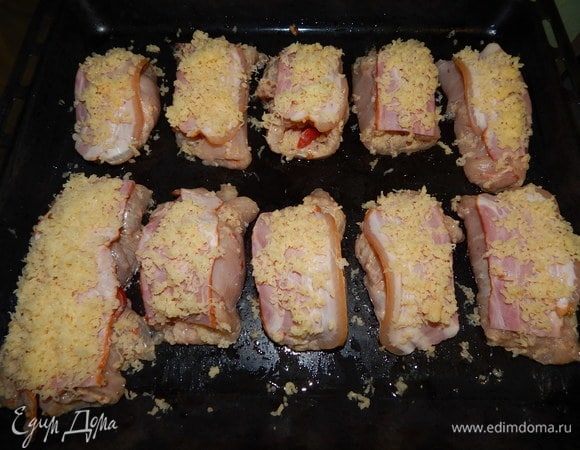 Рулетики выложить на смазанный маслом противень. Накрыть кусочком бекона и посыпать натертым сыром.