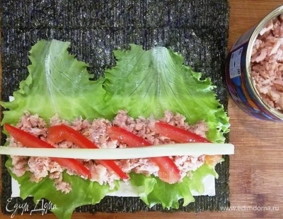 На листья салата в первом случае выкладываем салатный тунец (он более нежный по текстуре и более соленый). На тунец кладем помидор и огурец. Сворачиваем рулетом.