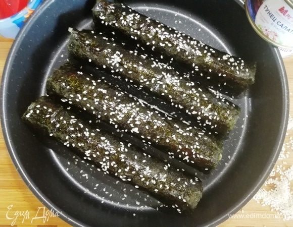 Выкладываем роллы на противень, смазываем маслом, оставшимся от филе тунца, и посыпаем кунжутом.