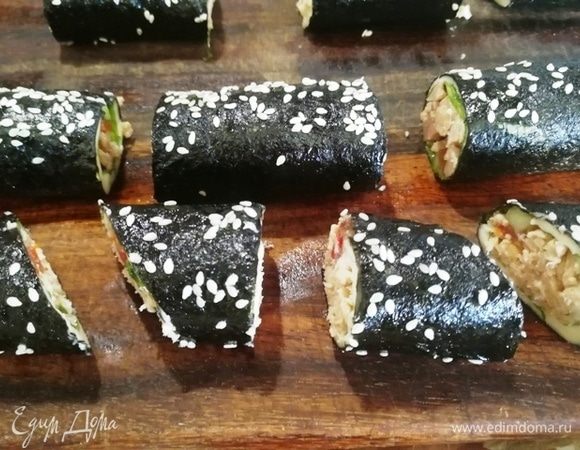 У запеченных роллов отрезаем неровные края, разрезаем роллы пополам и наискосок.