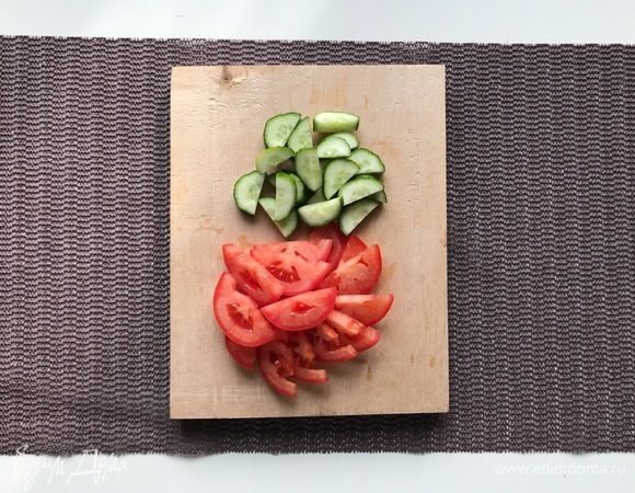 Помойте огурцы и помидоры, нарежьте. Зелень измельчите, чеснок мелко нарежьте.