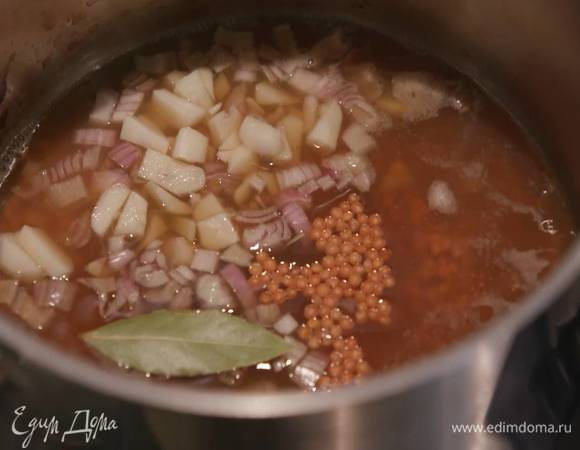 Чечевицу всыпать в кастрюлю, влить грибной бульон, добавить лук, чеснок, лавровый лист и отварить до готовности.