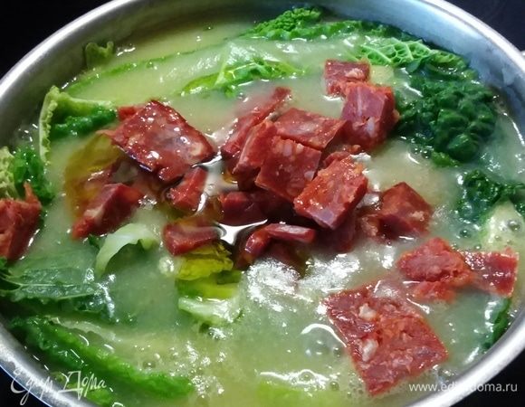 В суп добавить оливковое масло, капусту и колбасу. Варить на медленном огне до готовности капусты. Пока капуста готовится, чоризо отдаст супу свои вкусы, ароматы и цвет.