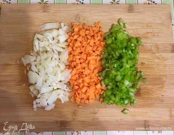 Нарежьте свинину и говядину и прокрутите через мясорубку. Почистите лук, морковь и сельдерей, мелко порубите. Разогрейте в большом и широком сотейнике оливковое и сливочное масла и обжарьте овощи до мягкости на среднем огне.