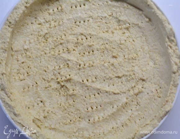 Влажными руками распределить тесто по форме, формируя бортики. Наколоть всю поверхность вилкой. Запечь в духовке при температуре 190°C в течение 15 минут.