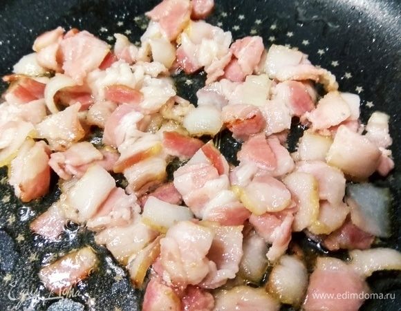 Бекон нарезаем кубиками и отправляем на предварительно разогретую сковороду. Слегка обжариваем бекон до мягкости.