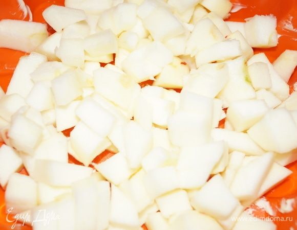 Смажьте форму маслом, на дно выложите очищенные и нарезанные на кубики яблоки.