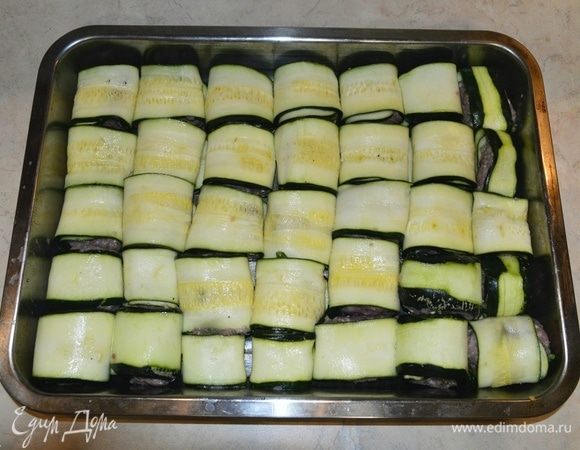 Противень смазать маслом. Выложить завернутые цукини плотно друг к другу.
