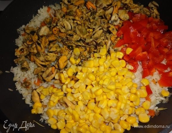 В сковороду с рисом и овощами добавить отваренное мясо мидий, консервированную кукурузу и сладкий красный перец, перемешать. Потушить под крышкой 5 минут и выключить огонь. Дать паэлье настояться 5–10 минут.