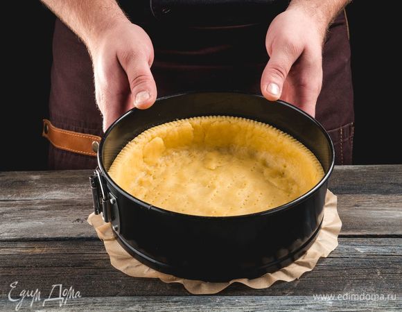 Утрамбуйте тесто в форму, формируя бортики по краям.