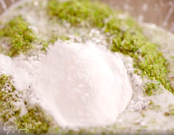 Приготовить глазурь: в чаше блендера соединить фисташки, оставшуюся кокосовую стружку и измельчить в крошку, затем влить кокосовое молоко, всыпать сахарную пудру и все перемешать.