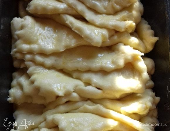 Затем под разным углом складываем нарезанное тесто в форму и﻿ даем немного подойти﻿﻿﻿﻿ ему. Держим под уклоном (я подкладываю скалку под один край). Между формочкой (нижняя часть) и тестом кладем кальку, сложенную в несколько раз.