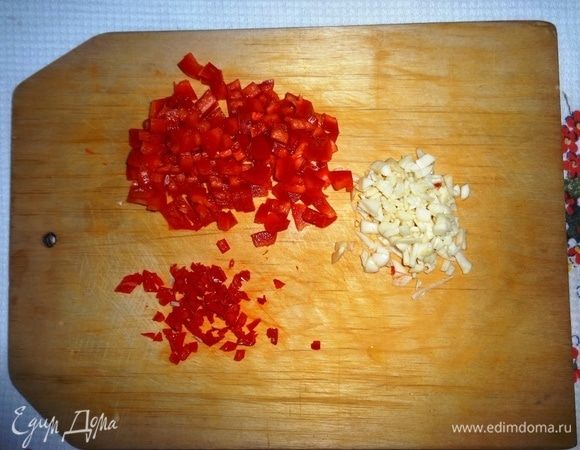 Подготовить начинку. Для этого сладкий и острый перцы вымыть, очистить от семян, нарезать мелкими кубиками. Чеснок почистить и тоже мелко нарезать.
