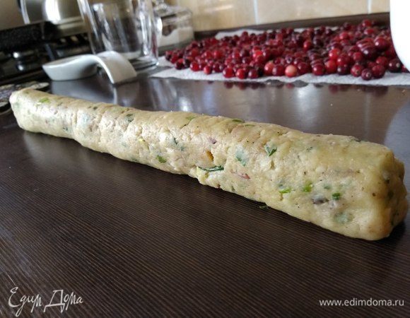 Добавить в тесто сыр, бекон и лук. Вымесить до пластичного состояния, скатать колбаску приблизительно 30 см длиной, завернуть ее в пищевую пленку и отправить в морозилку на 30 минут охлаждаться.