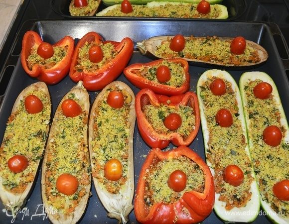 Распределяем нашу начинку в готовые запеченные овощи. Сверху посыпаем гратинати. Украшаем помидорами черри, разрезанными пополам. Отправляем в духовку, разогретую до 180°C, на 30 минут.