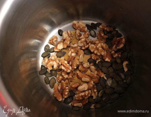 Поместить грецкие орехи (половинки, четвертинки ядер) и тыквенные семечки в сотейник с толстым дном.