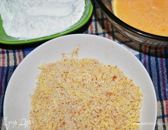 Подготовим все для жарки куриного филе. Берем 3 тарелки глубоких, в одну насыпаем муку, в другую 2 яйца разбиваем и хорошо взбиваем вилкой. В 3-ью тарелку насыпаем панировочные сухари. Далее натираем сыр пармезан и добавляем в панировку.