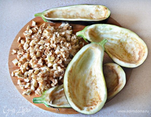 Баклажаны промыть, разрезать вдоль и с помощью ложки вынуть сердцевину так, чтобы получилась глубокая «лодочка». Полученные «лодочки» посыпать солью и оставить на 15 минут, сердцевину баклажанов мелко порубить.