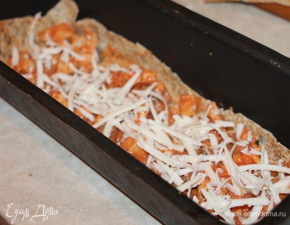 Выложить в смазанную маслом форму лист лаваша, на него часть начинки, сыр и так, чередуя выложить слои до верха формы.