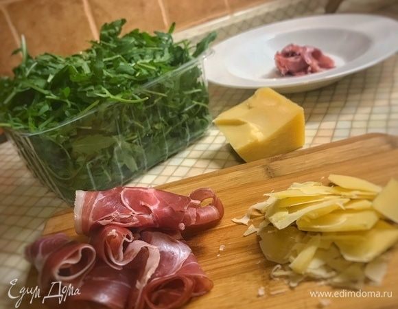 Руколу промыть и просушить (если требуется). Сыр натрите слайсами на боковой стороне терки. Прошутто хаотично порвите руками. Свиной окорок приобретайте лучше сразу нарезанный тонкими ломтями. Двух-трех ломтей на одну порцию вполне достаточно.