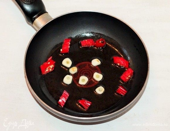 В другой сковороде на растопленных вместе сливочном (1 ст. л.) и растительном маслах (1 ст. л.) обжариваем нарезанные дольками острый перчик чили и очищенные зубчики чеснока. Жарим до появления аромата. Затем овощи удаляем, масло оставляем.