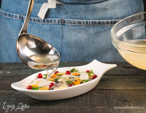 В сервировочные формы выложите нарезанные отварные овощи, нарезанные маслины, рыбу, клюкву и зелень. Залейте бульоном.