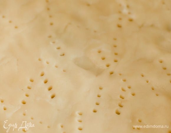 Часто наколоть тесто вилкой, накрыть бумагой для выпечки, всыпать любые бобовые и запекать корж в разогретой до 200°С духовке до легкого золотистого цвета.