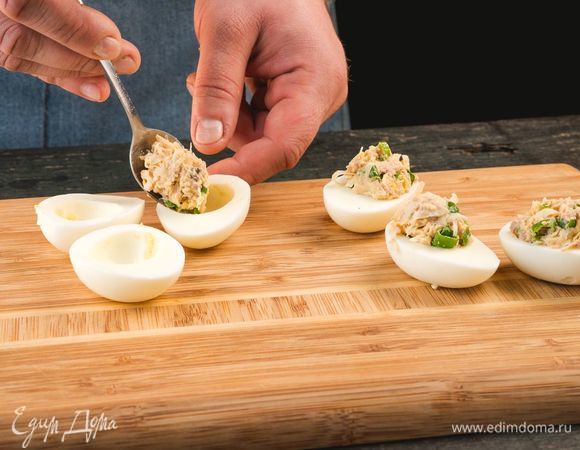Выложите начинку в половинки яиц, украсьте зеленью и зернами граната.