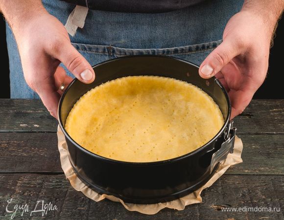По прошествии указанного времени достаньте тесто, уложите в форму, формируя из краев теста бортики. Дно наколите вилкой в нескольких местах.