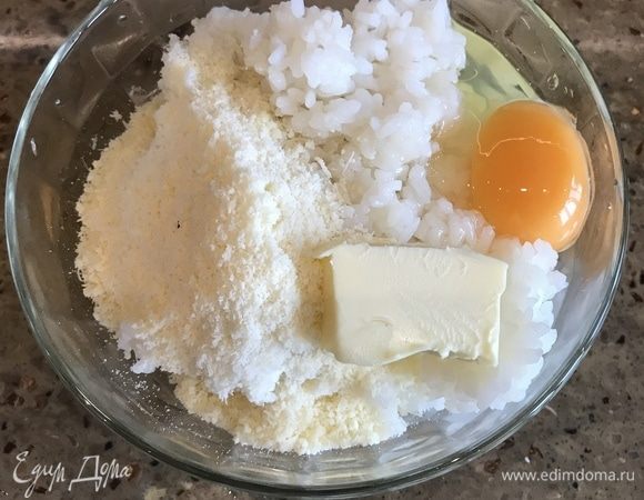 В миску с рисом добавляем куркуму, одно яйцо, размягченное сливочное масло. Хорошо перемешиваем все ингредиенты между собой, после добавляем сыр.