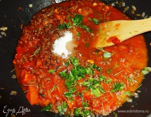 В соус всыпать сушеные орегано, розмарин, черный перец. Кладем нарезанный базилик, сахар и соль по вкусу. Влить красное вино, перемешать.