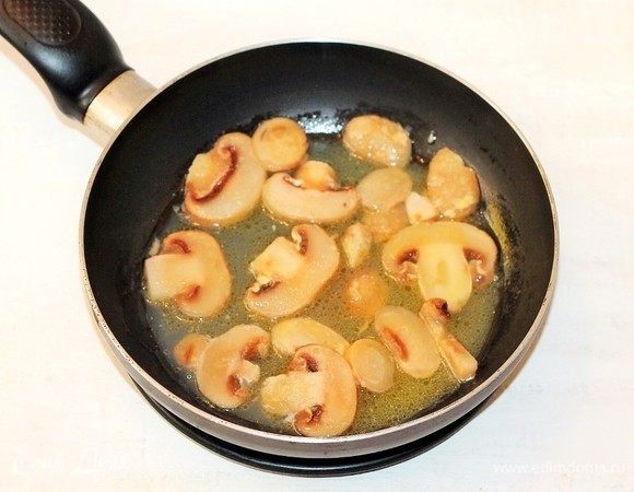 Приготовим начинку. Разогреваем сливочное масло в сковороде и обжариваем нарезанные пластинами грибы, постоянно помешивая, в течение 3–4 минут.