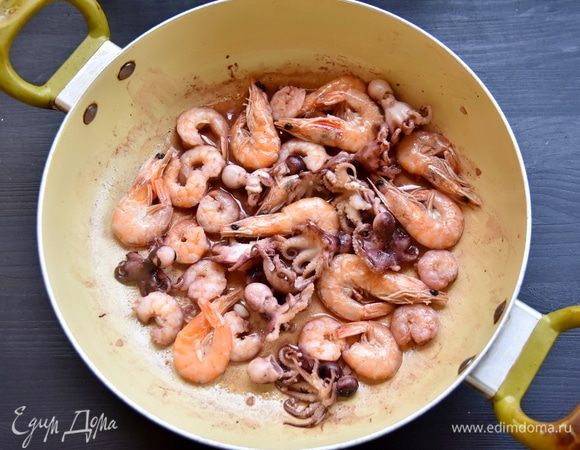 Для паэльи можно взять любые доступные морепродукты. Часть креветок очистите, а часть оставьте для украшения. В сковороде разогрейте 2 ст. л. оливкового масла и обжарьте морепродукты в течение 2–3 минут на сильном огне. Выложите обжаренные морепродукты в подготовленную миску.