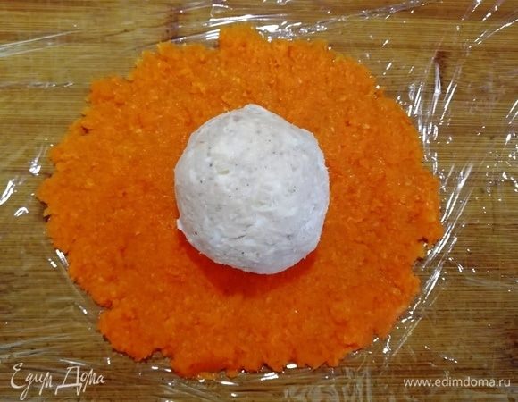 На рабочую поверхность выкладываем пищевую пленку, смазываем оливковым или растительным маслом. Выкладываем натертую морковь и разравниваем ее. На морковь кладем сырно-тунцовый шарик.