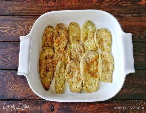 Выкладываем слой обжаренных баклажанов в тонкий равномерный слой.