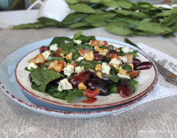 Собираем салат. Выкладываем порционно шпинат, виноград, бекон, крошим сыр, поливаем заправкой (если она успела остыть, то разогреваем ее) и посыпаем орешками. Подаем… И пусть всем будет вкусно! Приятного аппетита!