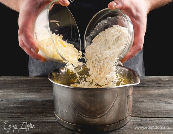 Постепенно подсыпайте муку и сыр. Энергично вымешивайте массу, чтобы не образовывалось комочков.