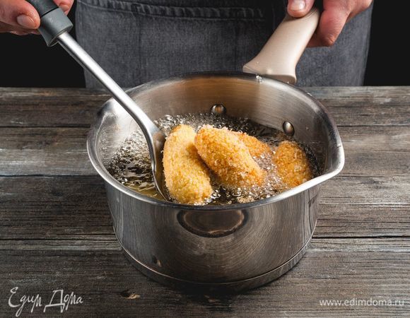 Разогрейте сотейник с растительным маслом и начинайте обжаривать крокеты. Погружайте их партиями по 4–5 штук. Жарьте, помешивая шумовкой, вынимайте через 3–4 минуты и перекладывайте на тарелку с бумажным полотенцем.