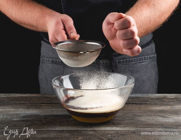 Смешайте муку с разрыхлителем и солью, начинайте просеивать в шоколадную массу, замешивая тесто.