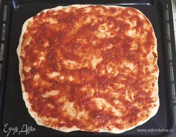 Далее тесто разделить на две части, раскатать два круга, намазать томатным соусом.