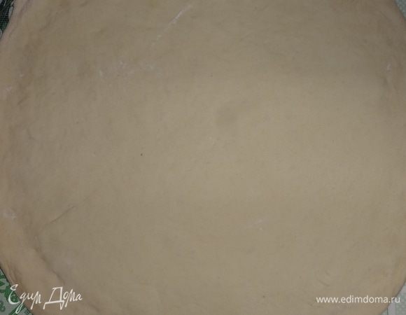 У меня получилось теста на 2 большие пиццы. Отделить половину теста и раскатать в круг толщиной примерно 0,5 см. У меня получился круг диаметром 29,5 см. Пальцами слегка распределить тесто к краю, чтобы получились небольшие бортики. Остальное тесто можно положить в морозилку, если не будете сразу использовать. Или хранить в холодильнике 1–2 дня, если будете использовать быстро.