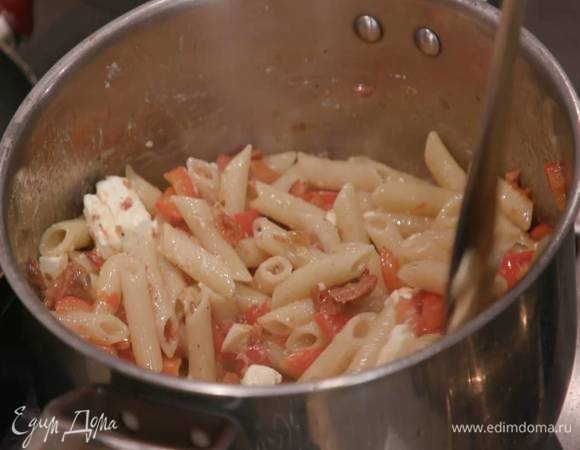 К отваренным макаронам выложить обжаренные овощи вместе с маслом, перемешать и поместить кастрюлю на огонь, добавить часть феты, влить немного воды, в которой варились макароны, еще раз перемешать и выключить огонь.