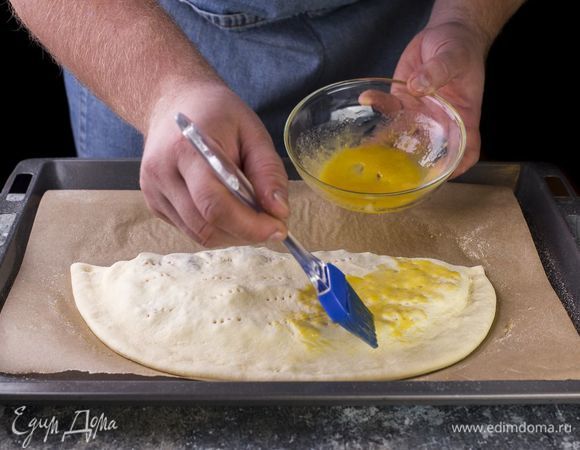 Накройте начинку второй половиной теста, защипните края, проколите вилкой. Смажьте пиццу оставшейся смесью из желтка и масла.