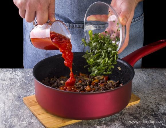 Добавьте фарш, помидоры в собственном соку, рубленую зелень и тушите до готовности.