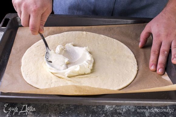 Раскатайте тесто в пласт, переложите на бумагу для выпечки. Основу для пиццы смажьте творожным сыром, смешанным с сахарной пудрой.